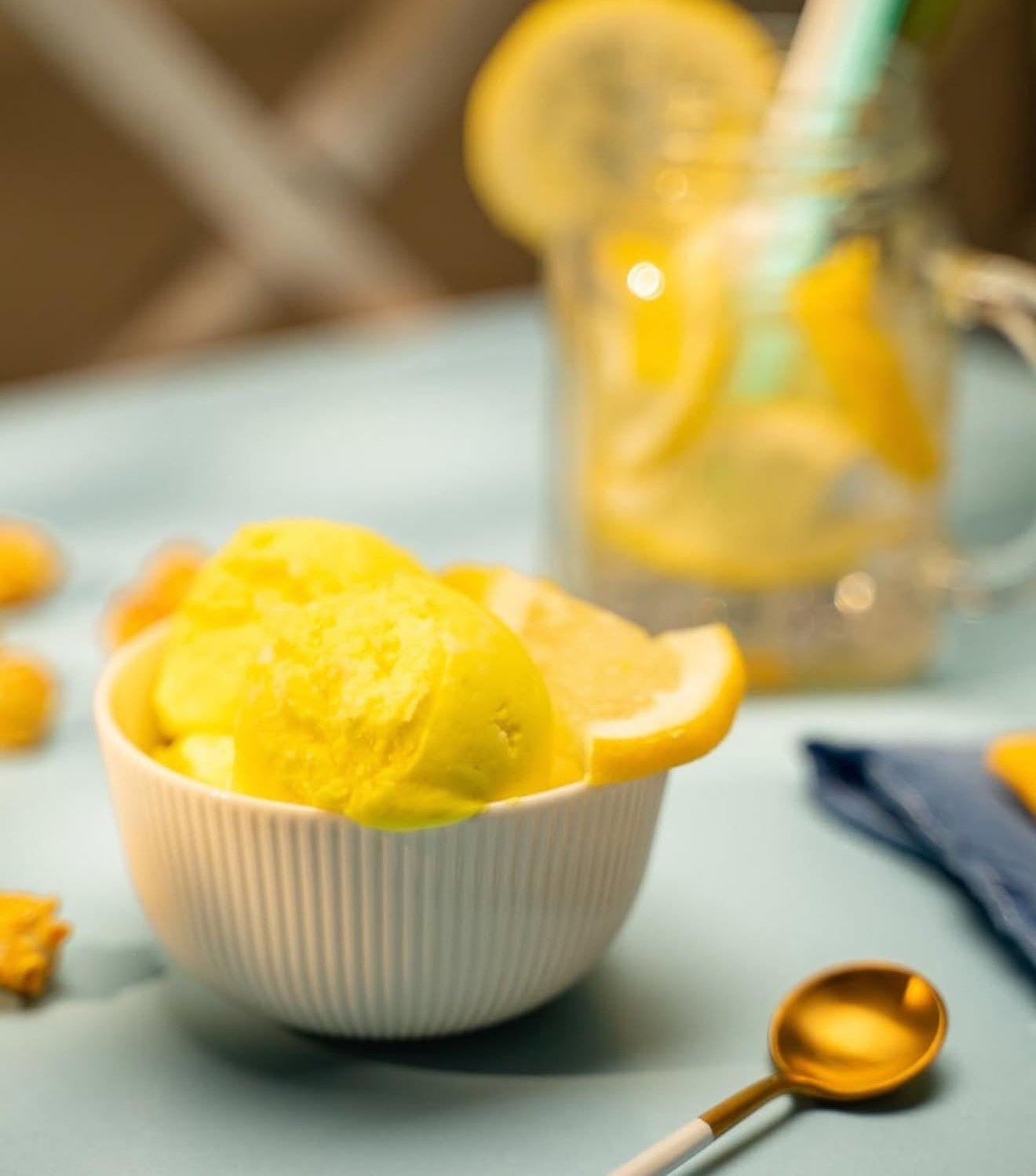Lemon sorbet in a ribbed bowl beside a jar of lemonade
